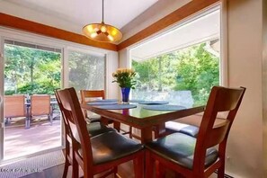 Enjoy meals in this cozy dining area with a table for four, comfortable chairs, and a beautiful view of lush greenery.