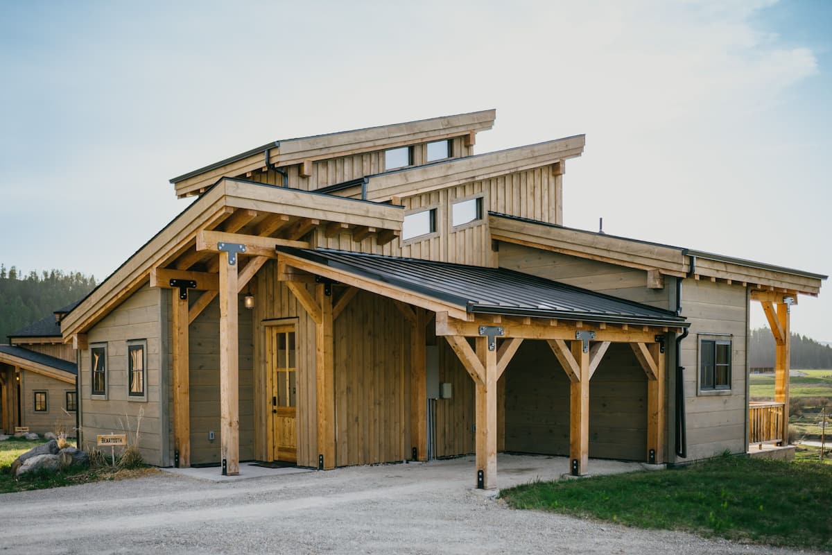 A wooden building with a sloped roof, large windows, and a covered porch area.