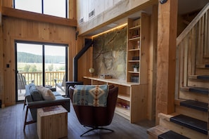 Un intérieur en bois comprenant un canapé, un fauteuil, un bureau et un escalier.