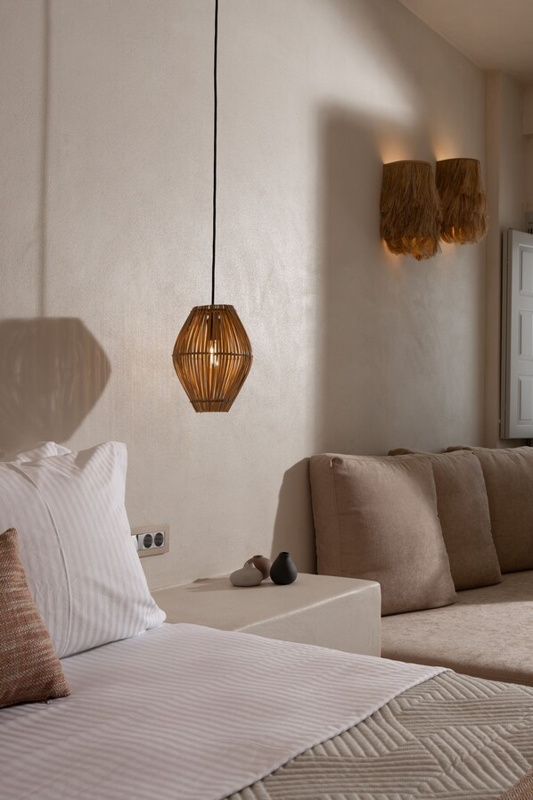 Een slaapkamer met een bed, nachtkastje en hanglamp.