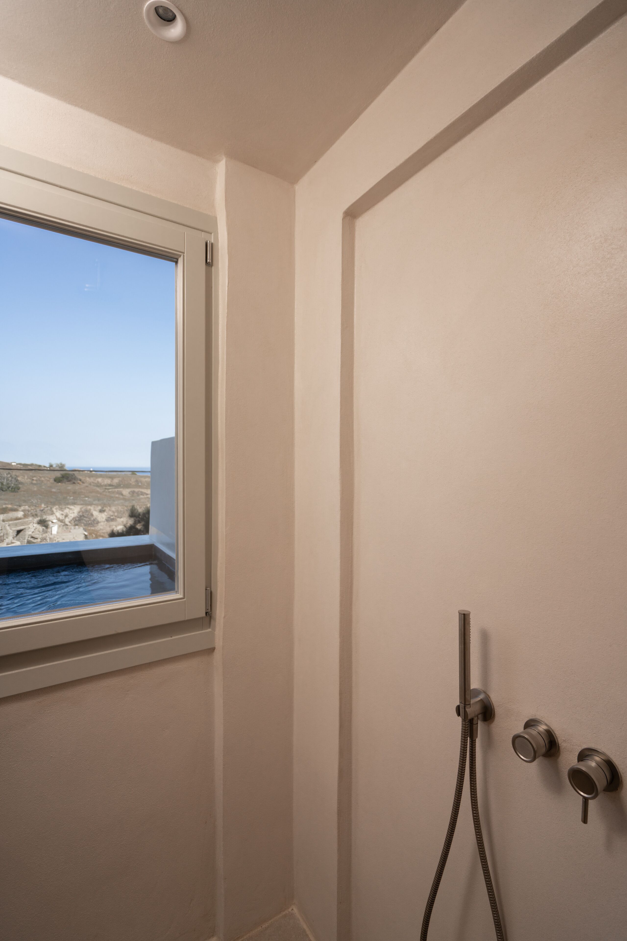 A bathroom with a shower, a window, and a view of the beach.