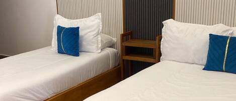 Una camera d'albergo con due letti singoli, pavimento in legno e vista su un paesaggio montano.