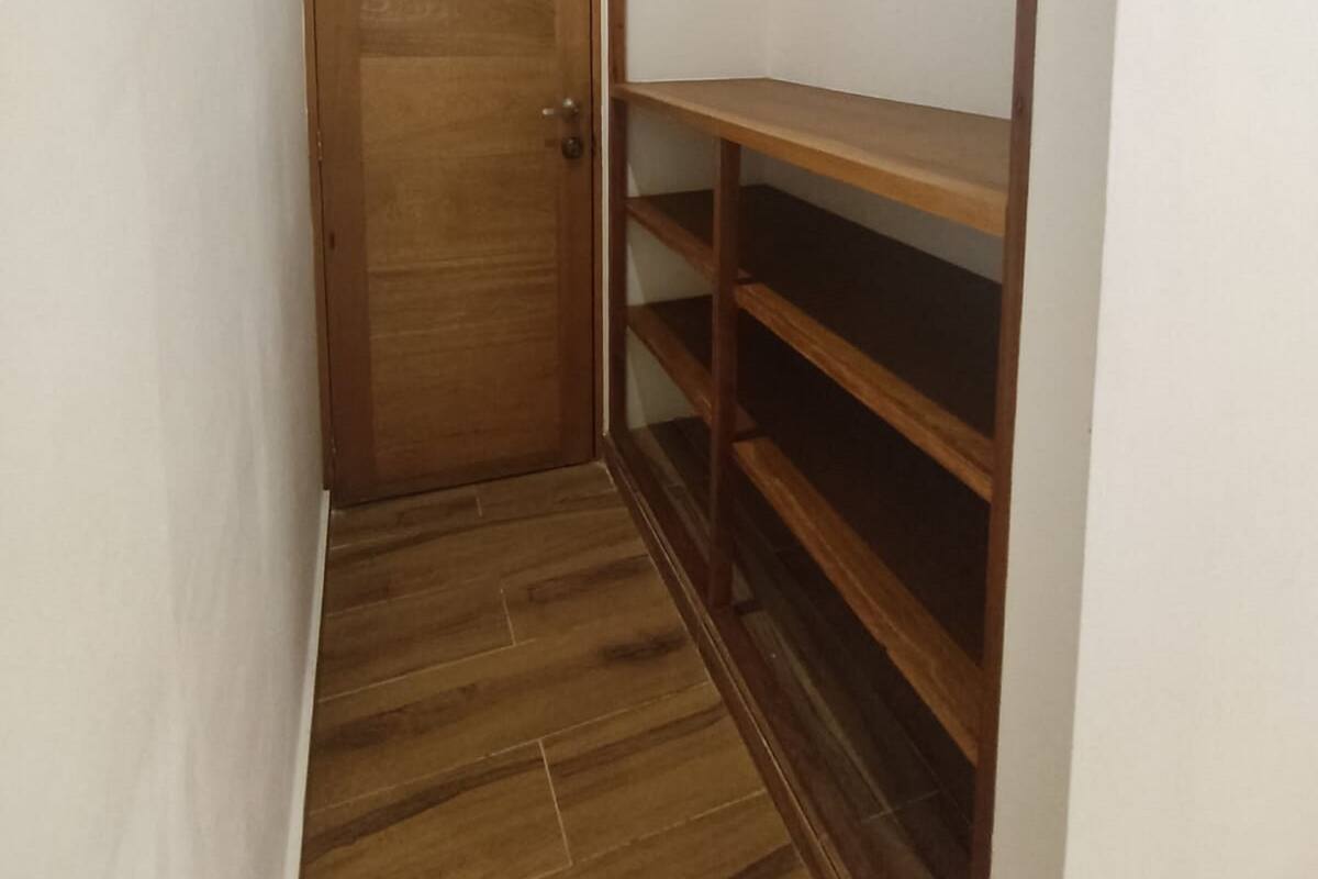 Un pasillo estrecho con una puerta de madera y estanterías empotradas.