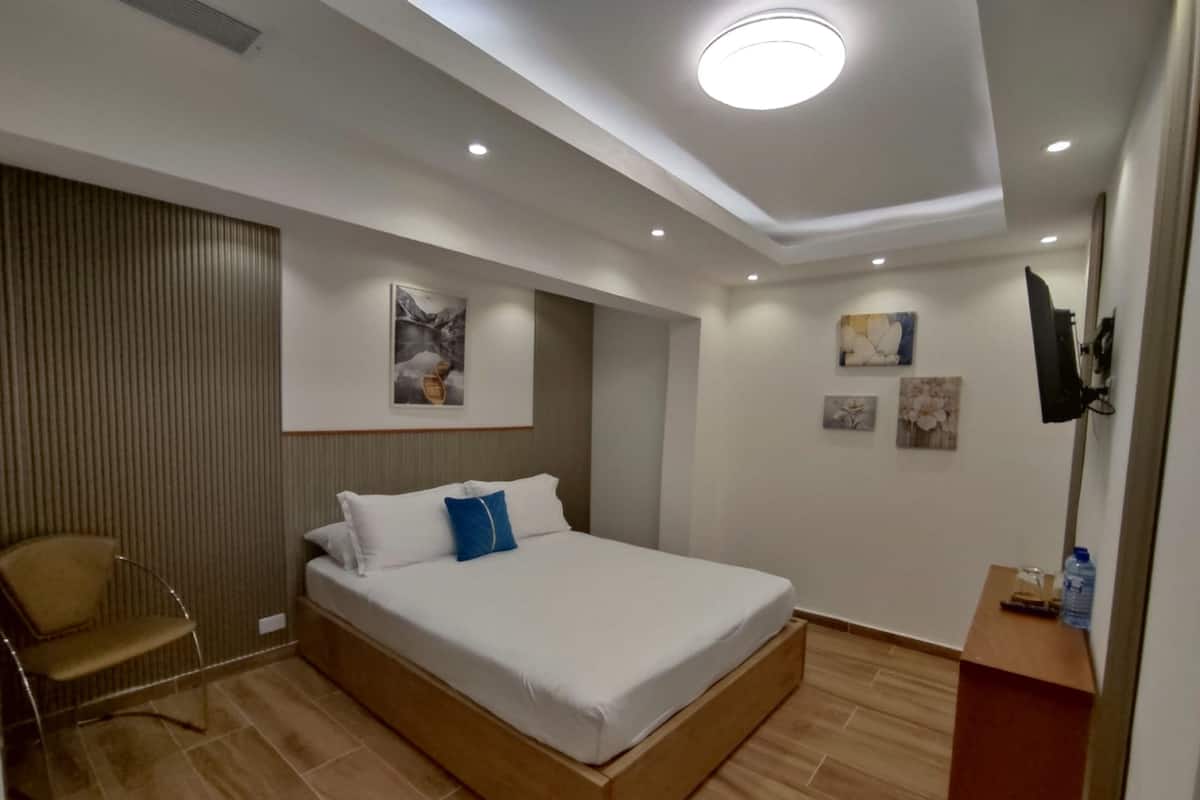 Un dormitorio moderno con una cama grande, una silla y un televisor de pantalla plana montado en la pared.