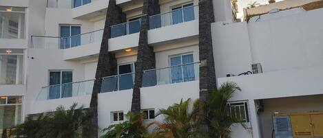 A multi-story building with balconies and a white facade.