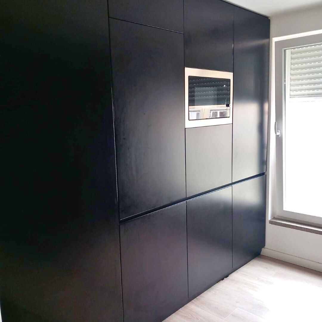 Ein Zimmer mit einem großen Kleiderschrank, einem kleinen Fenster mit Jalousien und einem hellen Boden.