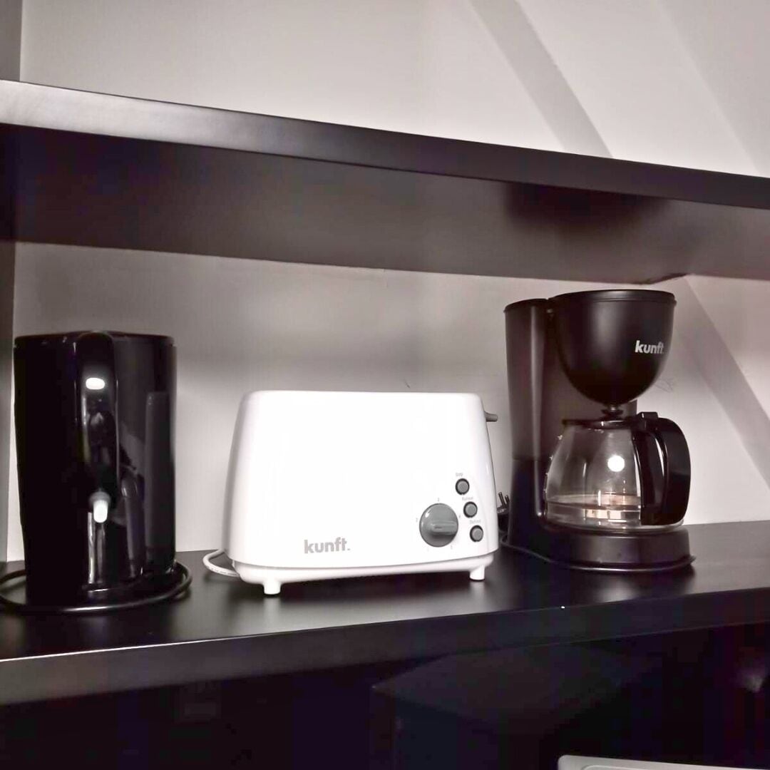 A kitchen counter with a white toaster, a black coffee maker, and a black mug.