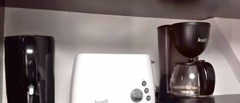 A kitchen counter with a white toaster, a black coffee maker, and a black mug.