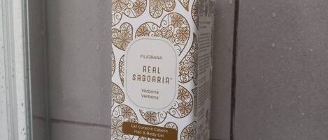 A bottle of Filigrana Real Saboaria hair and body gel on a white shelf against a tiled wall.