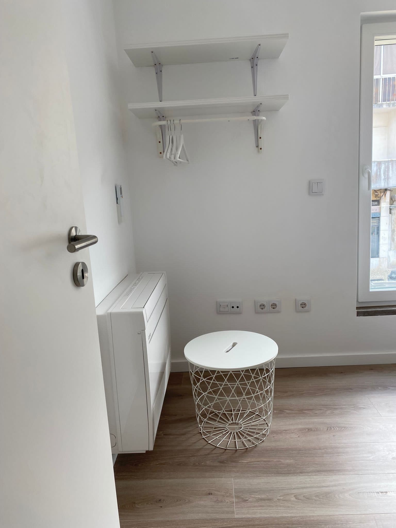 Ein modernes Badezimmer mit einem weißen Waschbecken, einer weißen Toilette und einem weißen Heizkörper. Es gibt einen runden, weißen Tisch mit einem geometrischen Muster.