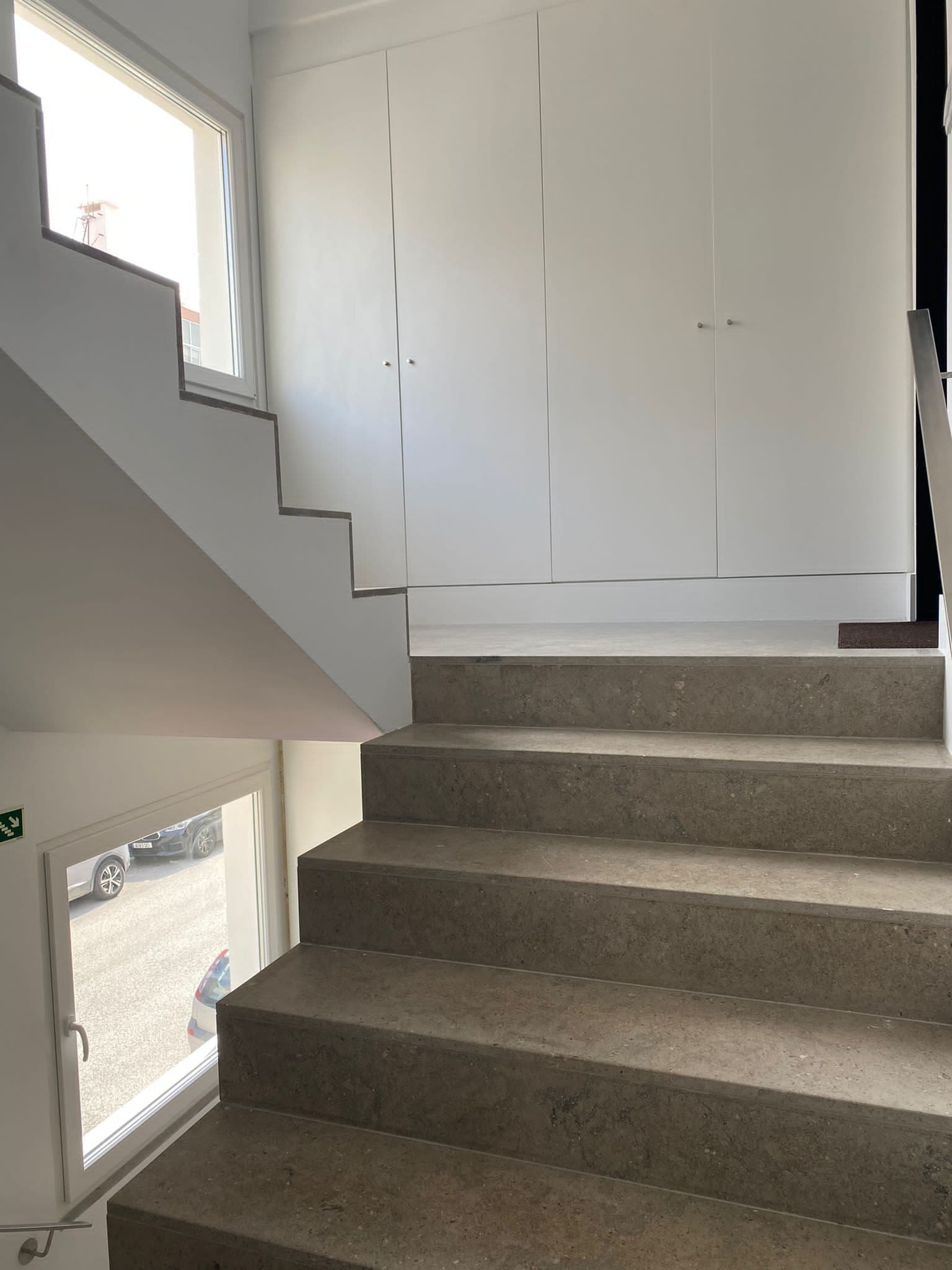 Una escalera de hormigón con peldaños que conducen a un rellano con puertas blancas.