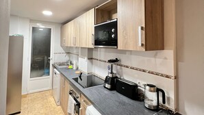 Eine moderne Küche mit Holzausstattung, einer eingebauten Mikrowelle, einer Kaffeemaschine und einem Geschirrspüler.