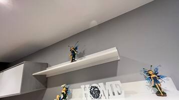 Tres repisas blancas con figuritas de hadas y un letrero que dice 'HOME'.