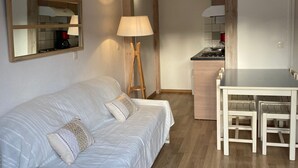 Une pièce à deux niveaux comprenant un lit, un bureau et une chaise. Un miroir est accroché au mur et une lampe se trouve sur le sol.