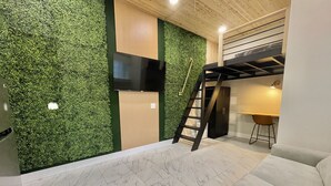 A modern interior with a green wall, a flat-screen TV, a wooden ceiling, a staircase, and a seating area. - Modern Ocala Studio Cabin (Ocala)