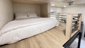 A bedroom with a bunk bed, wooden ceiling, and a small desk with a chair. - Modern Ocala Studio Cabin (Ocala)