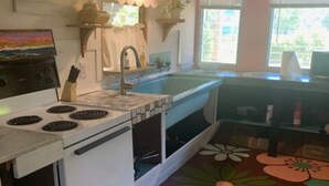 Una cocina con estufa blanca, pileta y piso con estampado floral.