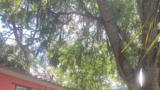 Una casa roja con porche, escalones de madera y cuatro sillas.