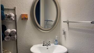 A bathroom with a white sink, a mirror, a towel rack with towels, and a toilet.