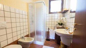 A bathroom with a toilet, bidet, sink, and a window above the mirror. - Agriturismo Alla Poncia - Monolocale 3 (Gravedona)