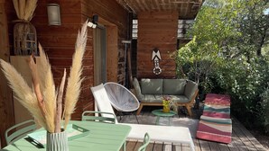 A wooden deck with a green table, chairs, and a sofa. There are pampas grass decorations and a small plant on the table.