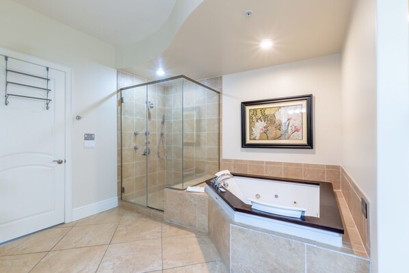A modern bathroom with a glass-enclosed shower, a bathtub, and a framed floral artwork on the wall.