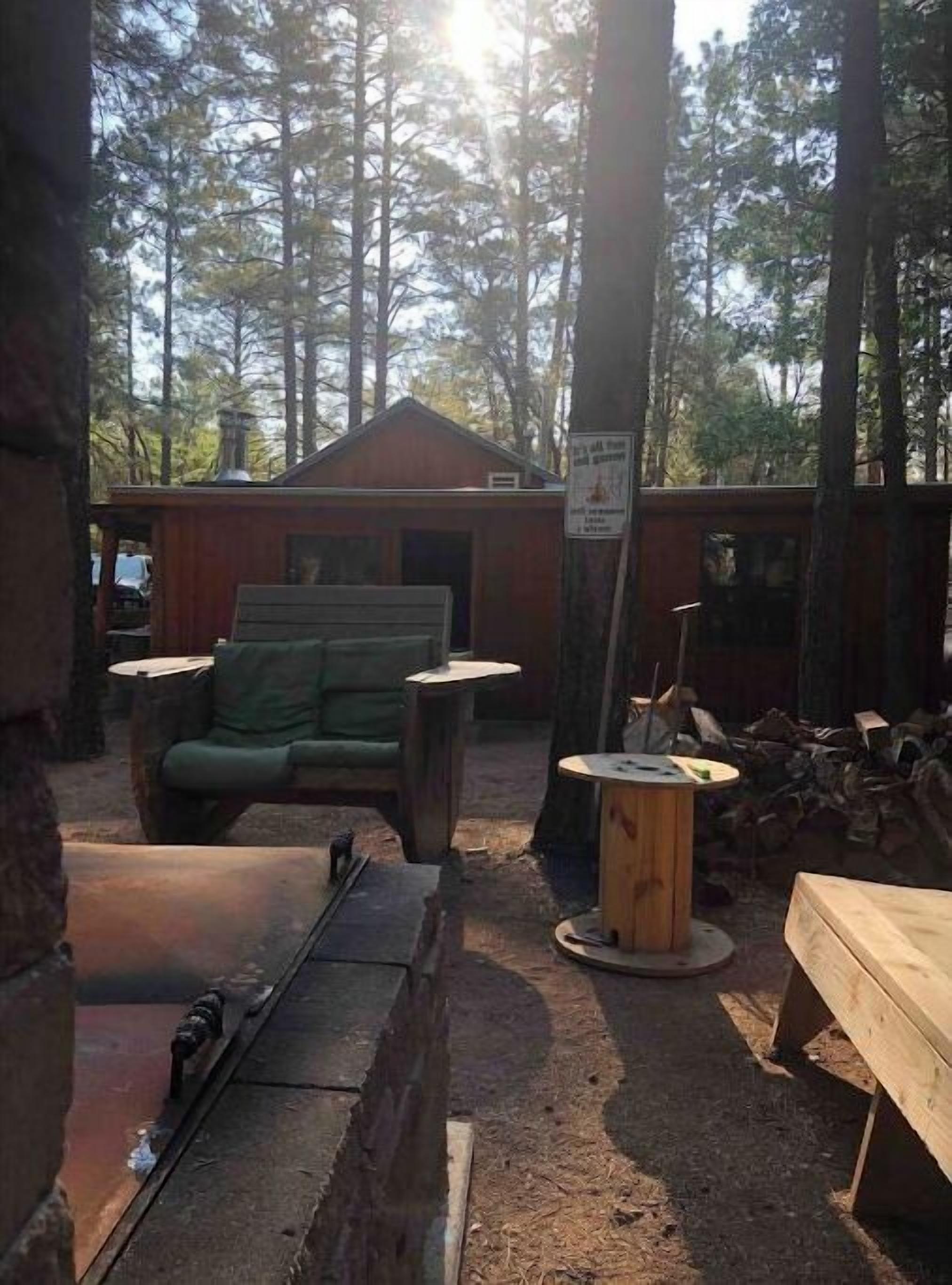 A rustic cabin with a green couch, a small table, and a fireplace.