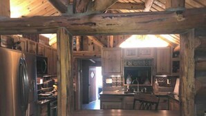 A rustic kitchen with wooden cabinets, a refrigerator, and a dining table with chairs. - Fully fenced yard, dogs welcome!  (Lakeside)