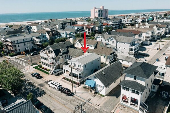 Un quartier résidentiel situé sur la côte, avec des maisons, une plage et un grand immeuble en arrière-plan.