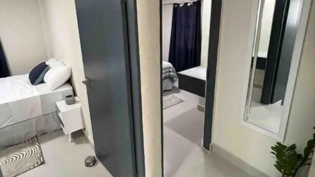 Een moderne hotelkamer met een bed, nachtkastje en een grote spiegel.