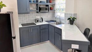Een moderne keuken met grijze kastjes, een magnetron, een spoelbak en een aanrecht.