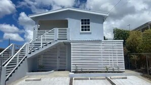 Een tweelaags huis met een trap die naar de bovenverdieping leidt, een garagepoort en een heldere lucht met wolken.