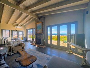 Amplia sala de estar con chimenea, ventanas grandes y vistas al exterior.