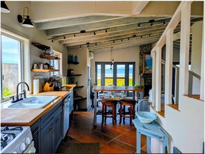 Una cocina con un ventanal grande, un comedor con sillas y vistas a la playa.