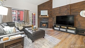 Una sala de estar moderna con chimenea, sofá de cuero y televisor de pantalla plana.