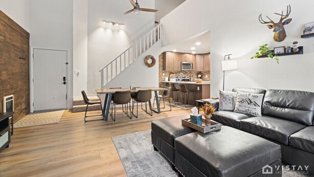 Un amplio salón con una cocina moderna, un comedor y una escalera que sube a un nivel superior.
