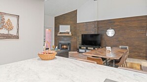 Una sala de estar moderna con chimenea, televisor y comedor con mesa y sillas de madera.