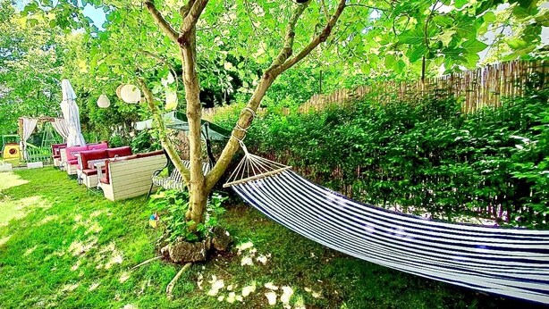 Um jardim com uma rede, uma mesa pequena e uma cadeira.