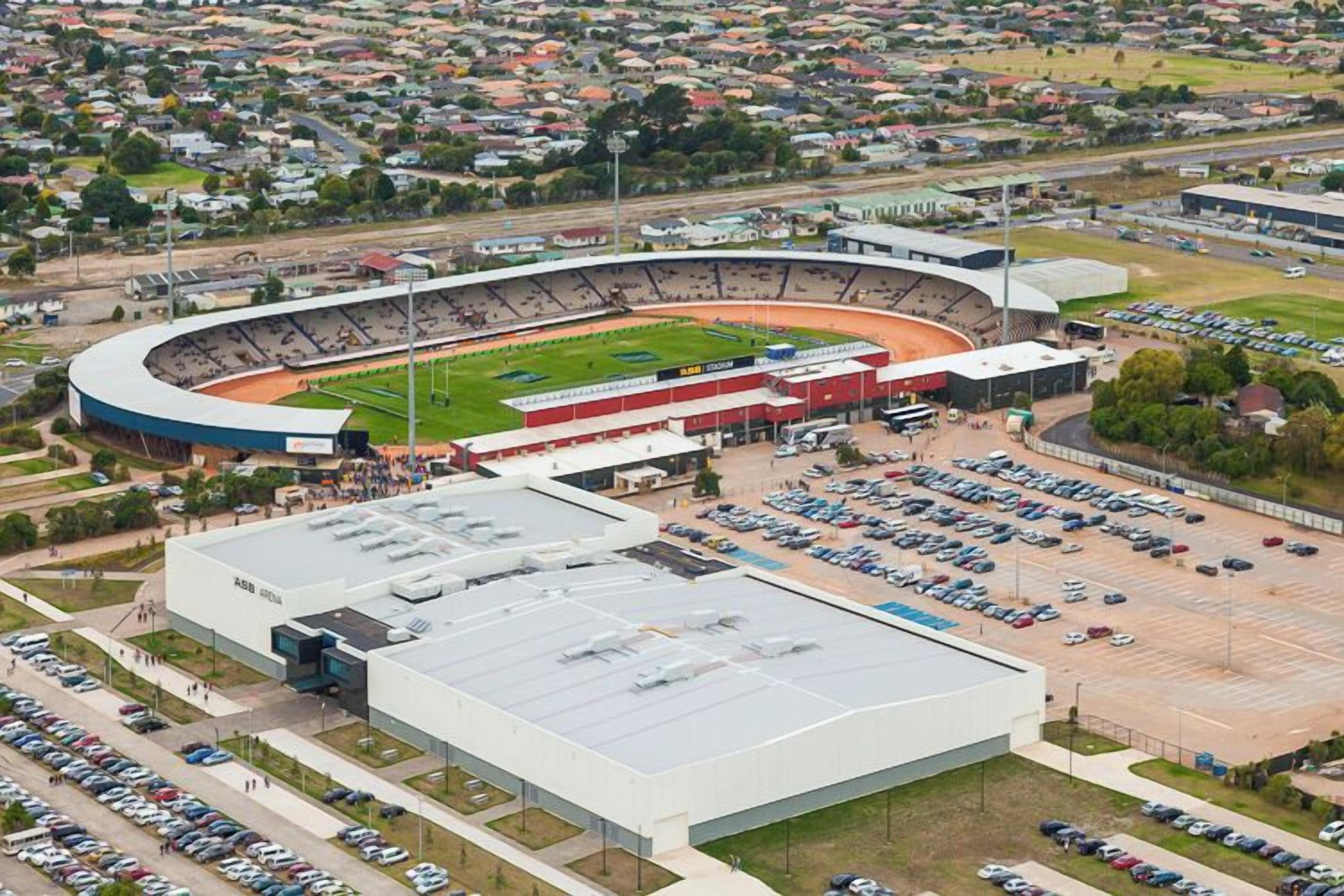 A stadium with a large parking lot and a building with a flat roof.