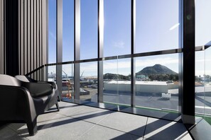 Un intérieur moderne avec de grandes fenêtres, un fauteuil noir et une vue sur un paysage montagneux.