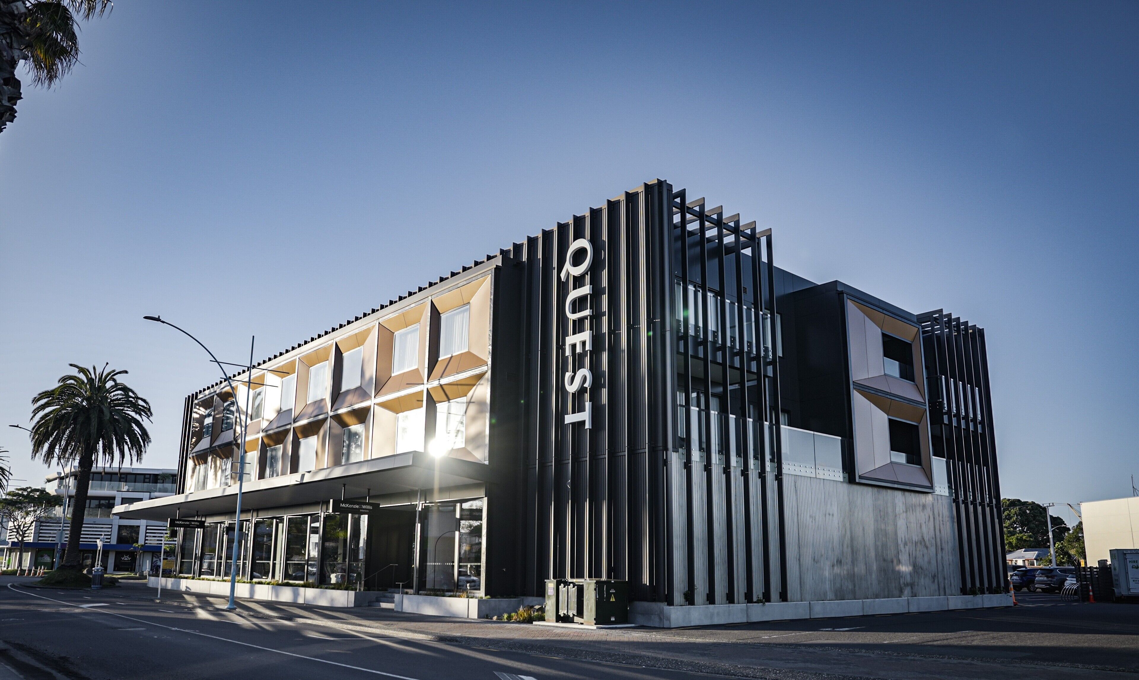 Un hotel moderno con un llamativo letrero 'QUEST', amplias ventanas y una fachada limpia.