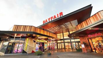 A modern building with a prominent 'Bayfair' sign, a 'Timezone' store, and a 'Noodles' restaurant.