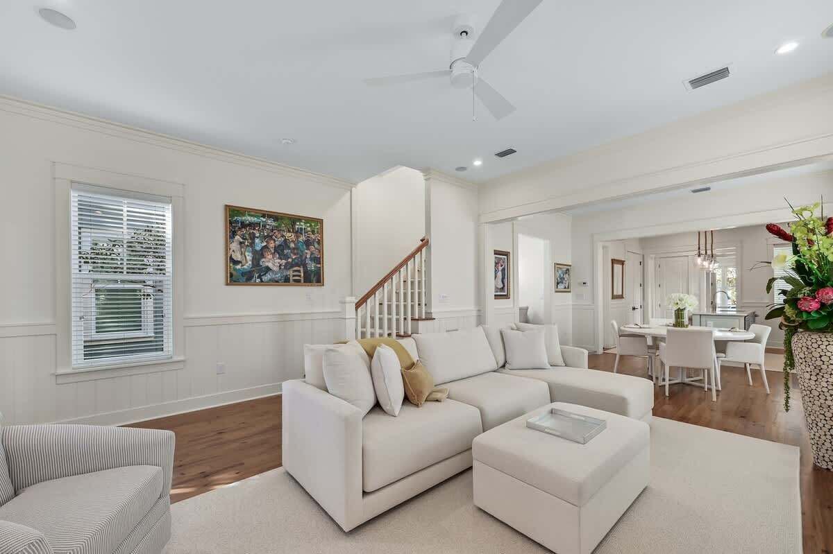 A spacious living room with a white sofa, a striped chair, and a dining area with a white table and chairs.