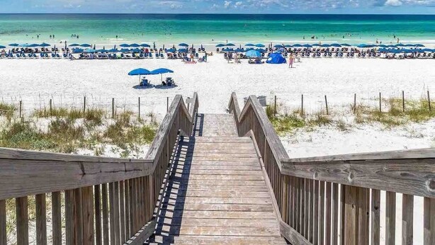 A wooden boardwalk leading to a beach with umbrellas and people. - Watercolor House: Beach Access, & Family Fun! (Santa Rosa Beach)