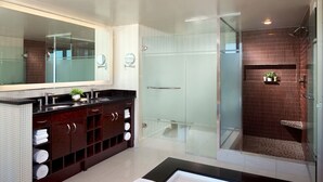 Een moderne badkamer met een douchecabine van glas, een grote spiegel en een donker houten wastafelmeubel.