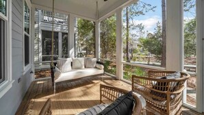 A covered porch with a white sofa, wicker chairs, and a ceiling fan. - Luxury Watercolor House: Beach Access & Golf Cart (Santa Rosa Beach)