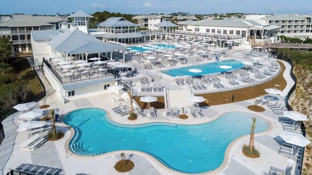 A resort with multiple swimming pools, sun loungers, and a large building with a tower. - Luxury Watercolor House: Beach Access & Golf Cart (Santa Rosa Beach)