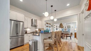 A modern kitchen with white cabinetry, stainless steel appliances, and a central island with seating. - Luxury Watercolor House: Beach Access & Golf Cart (Santa Rosa Beach)