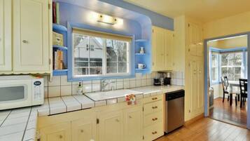 A kitchen with white cabinets, a microwave, a sink, and a window.