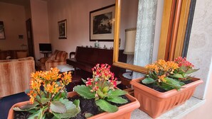 Un salon avec un canapé, des fauteuils, un piano et des plantes en pot.
